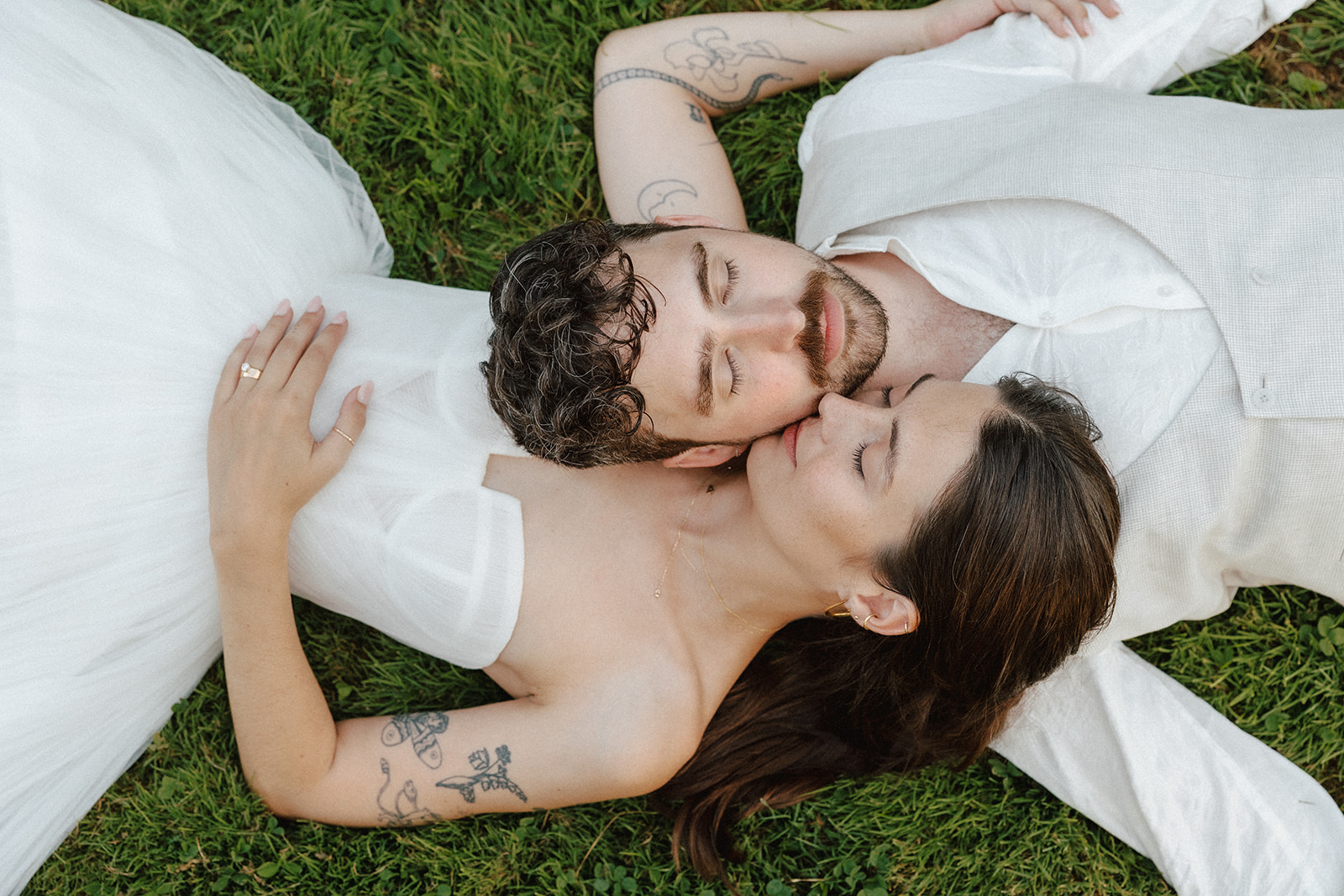 Documentary wedding photography of an artistic, non-traditional Vermont couple laying head-to-head in the green grass at the Intervale Center in Burlington vermont